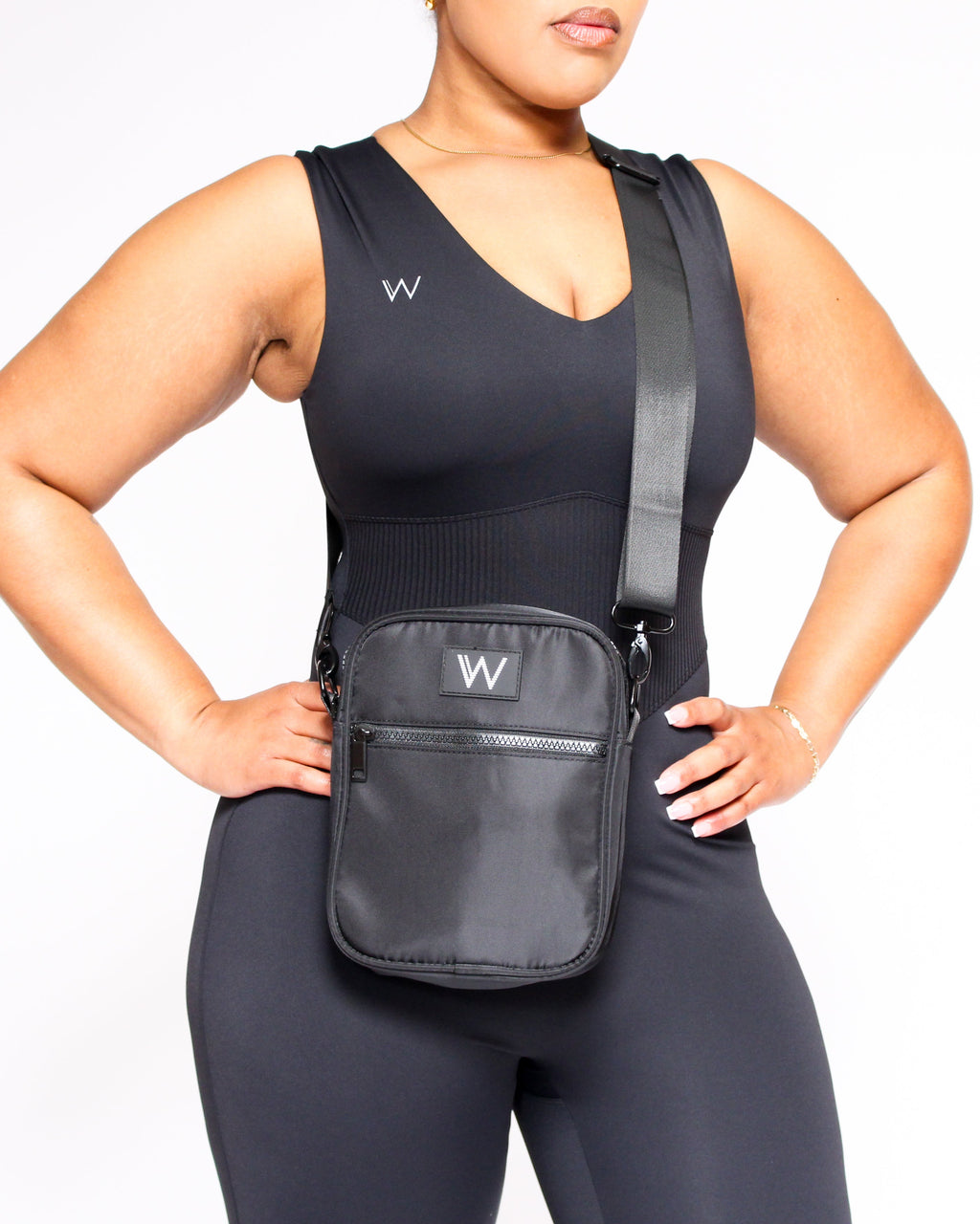 Person wearing a black tank top and leggings with a matching crossbody bag on a white background